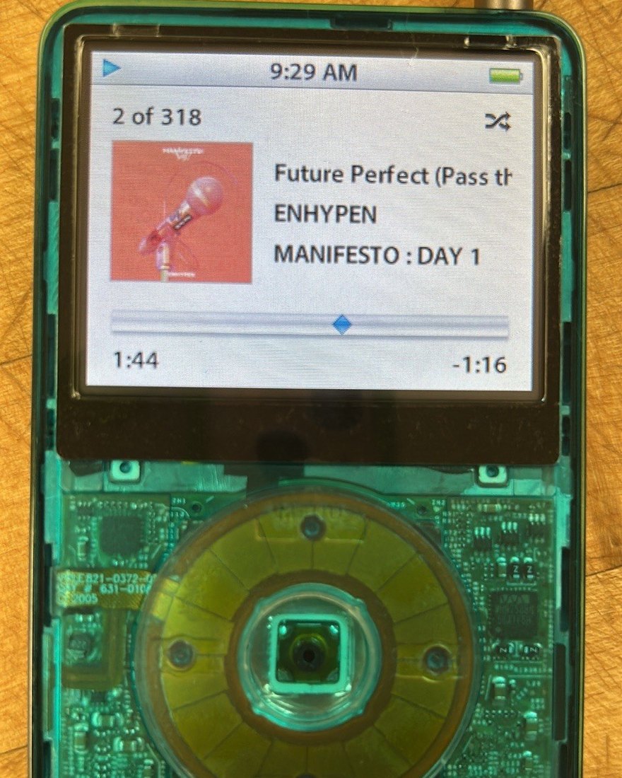 Close-up of a green translucent iPod Classic, the click wheel and board showing through the tinted shell.